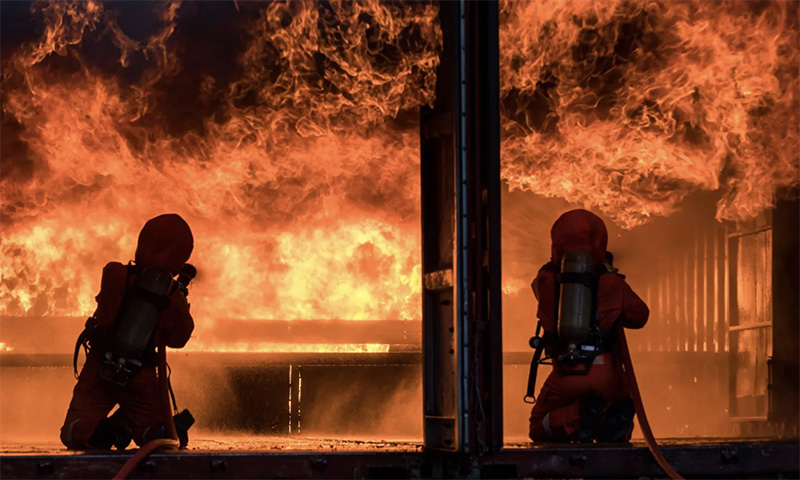 Firefighters combating intense flames, showcasing the importance of The Wildfire Guardian™ wildfire protection and fire-retardant technology